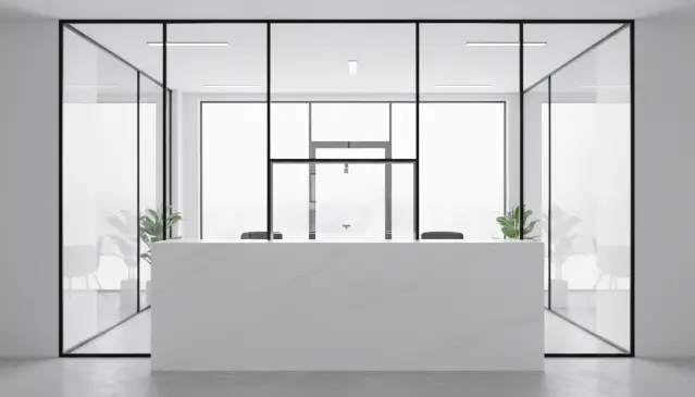 Szklana zabudowa recepcji z okienkiem podawczym w jasnym wnętrzu.